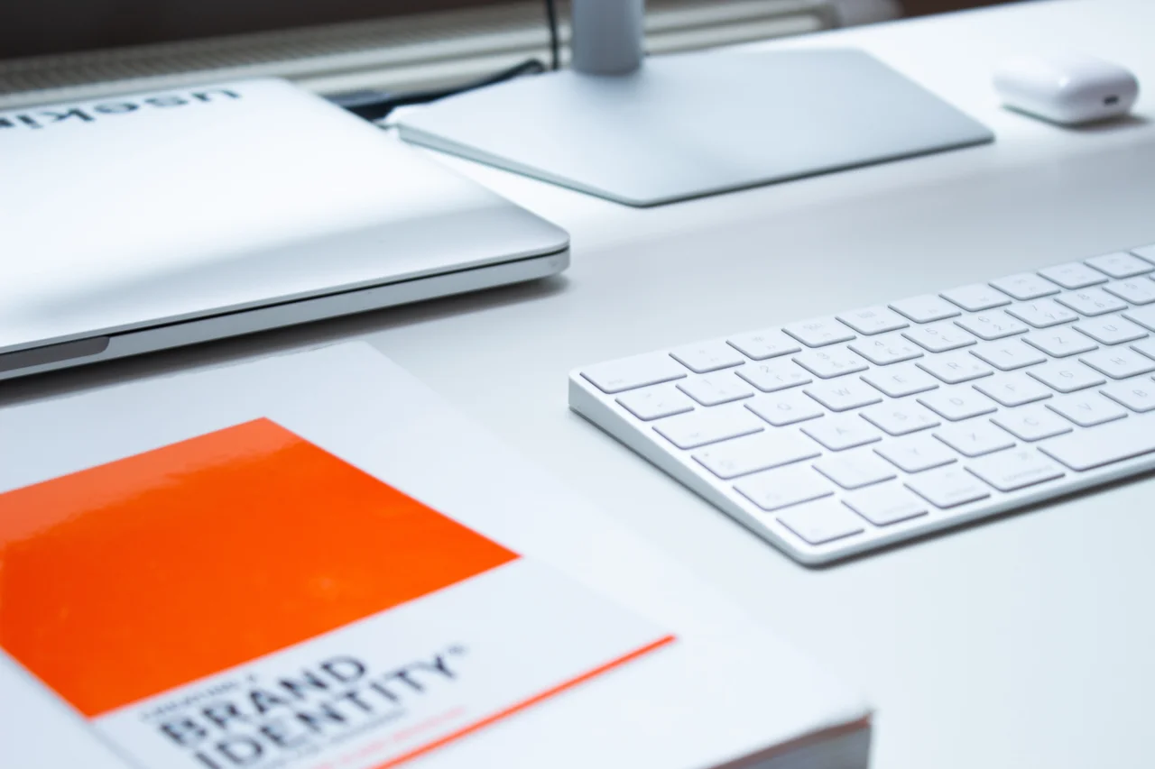 a book about brand identity, a laptop and a keyboard